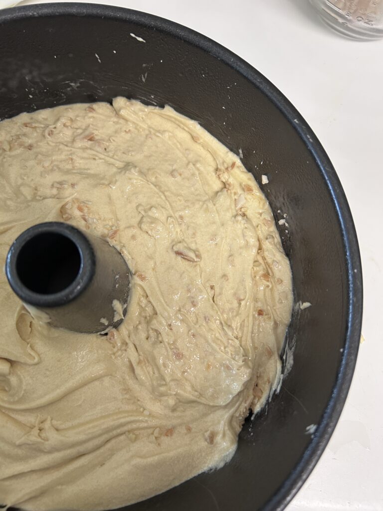 cake batter in a black cake tin. 