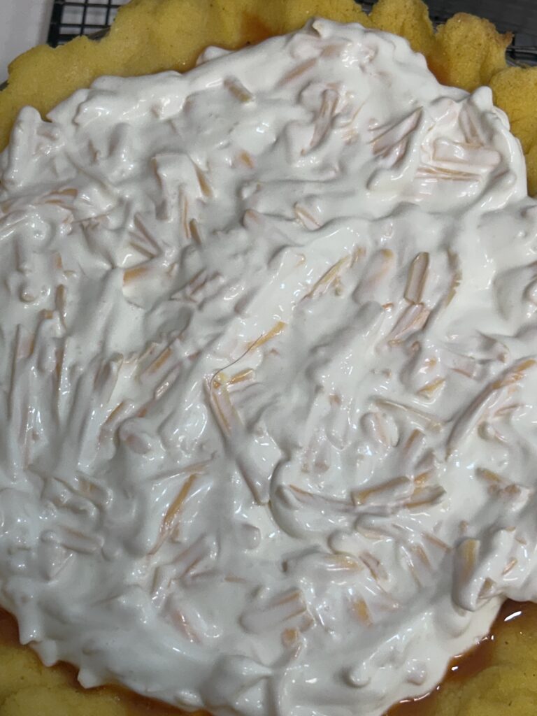 Pie being topped with sour cream and cheddar topping before baking 