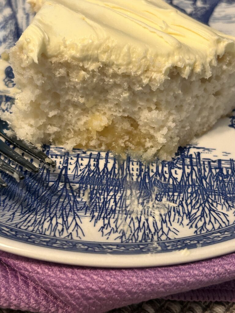 a slice of lemon love cake on a blue and white plate with one bite taken.