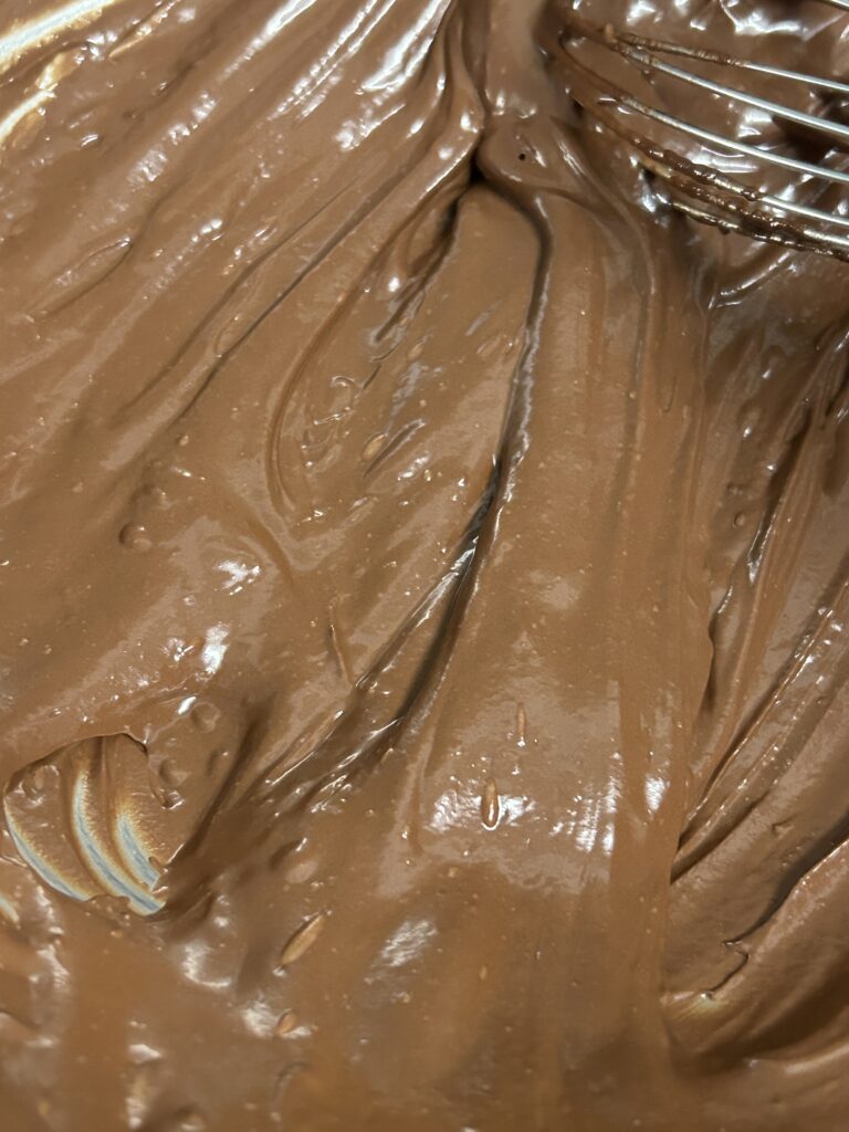 brownie batter being stirred with. a metal whisk in a bowl.