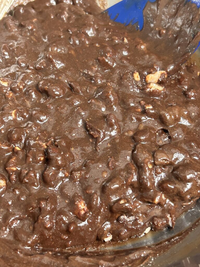 chopped nuts being stirred into brownie batter.