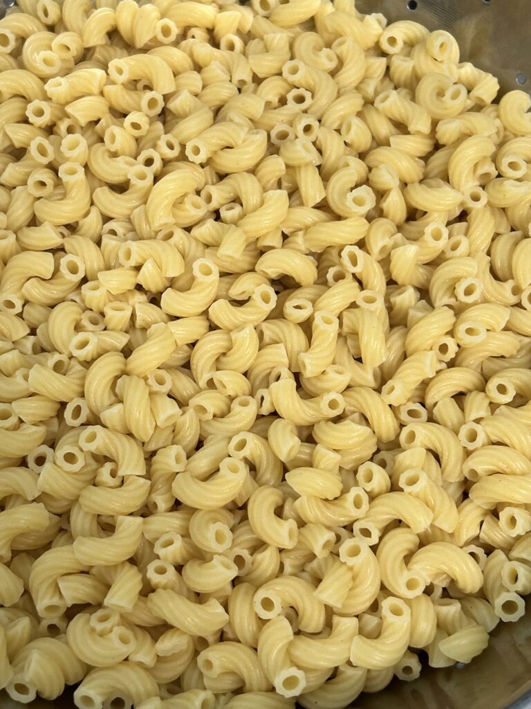 cooked macaroni pasta cooling in a metal bowl.