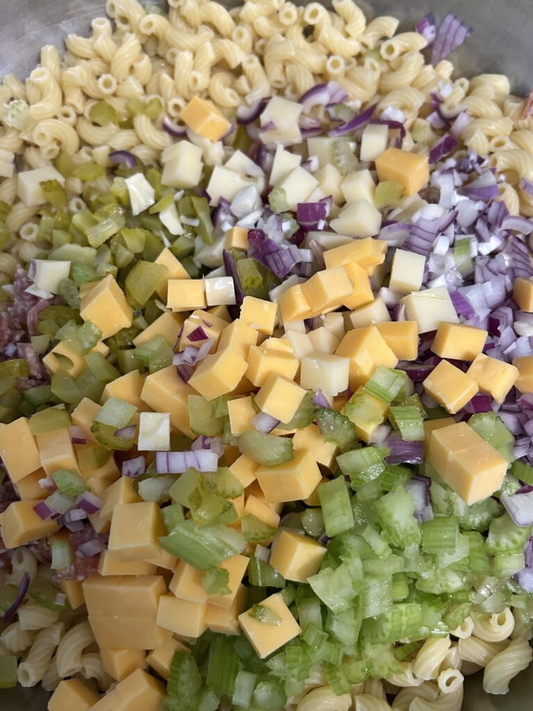 chopped ingredients being added to cooked pasta.