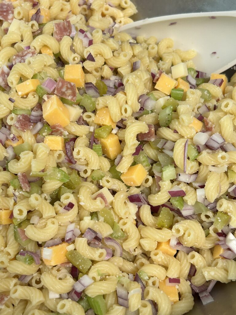 cooked pasta and chopped up ingredients in a metal bowl.